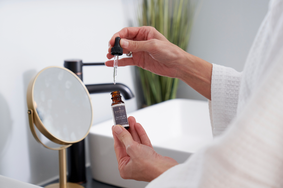 Dropping Hyaluronic Acid Facial Serum onto fingertips at the vanity