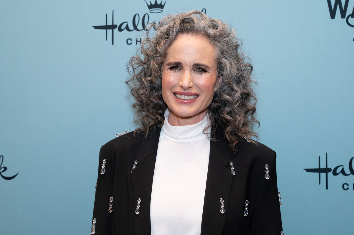 Smiling woman with silver curly hair at a media event