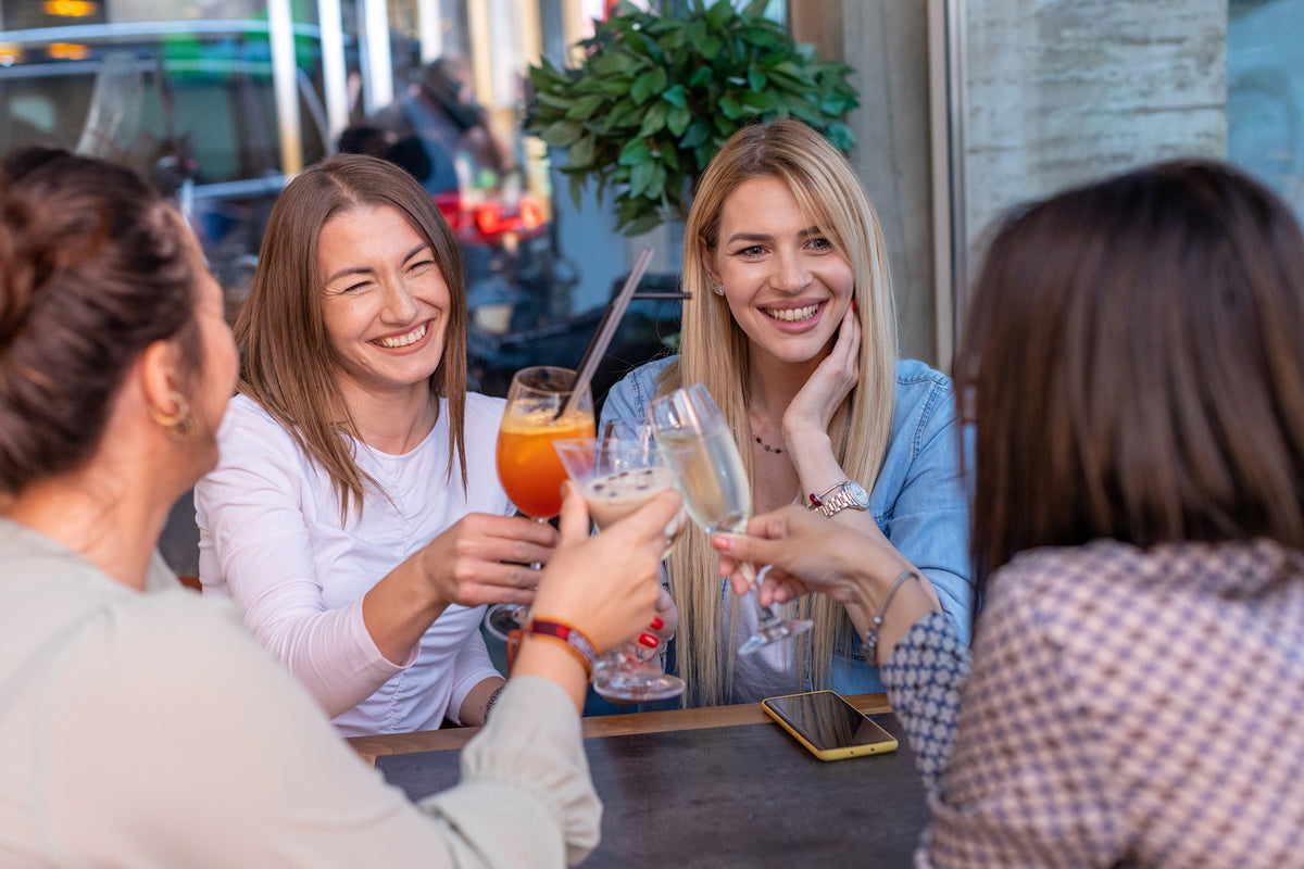 Friends laughing and toasting with drinks at a table