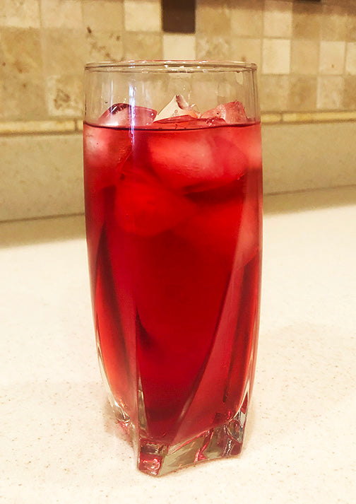 Tall glass of ruby-red beauty water with ice