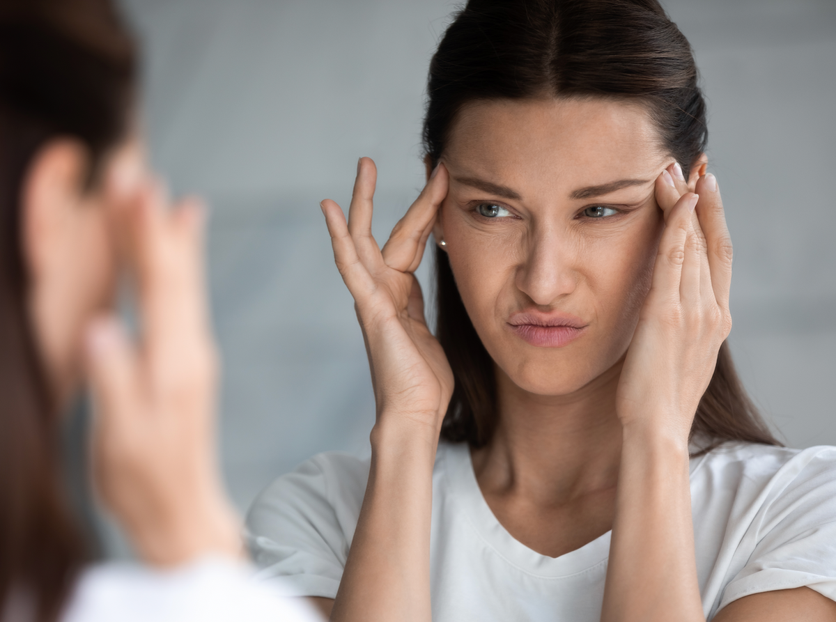 Woman holding her temples with a pained expression