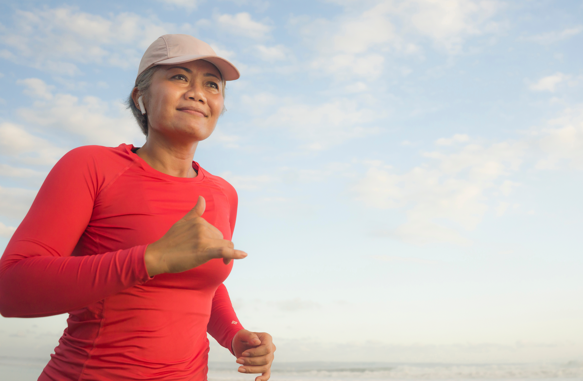 Smiling woman in a cap and red top on a seaside walk