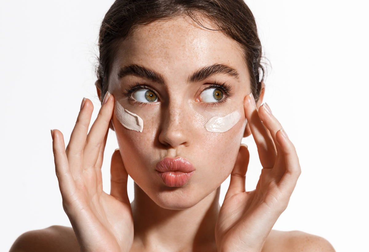 Woman with dabs of cream on her cheeks making a playful face