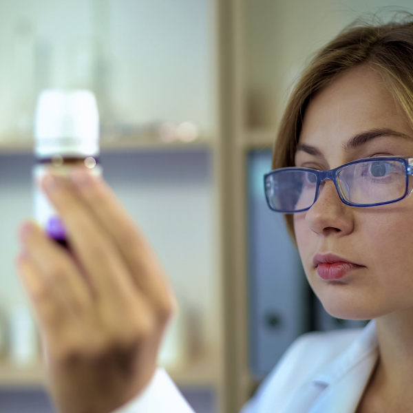 Woman in glasses examining a skincare bottle in a lab