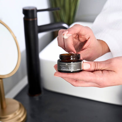 Hands holding an open jar of Vitamin Boost Eye Repair Cream