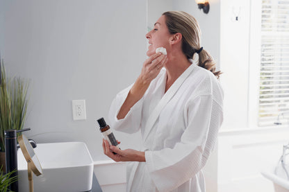 Woman applying Rose Aloe Hydrating Toner with a cotton pad at the sink